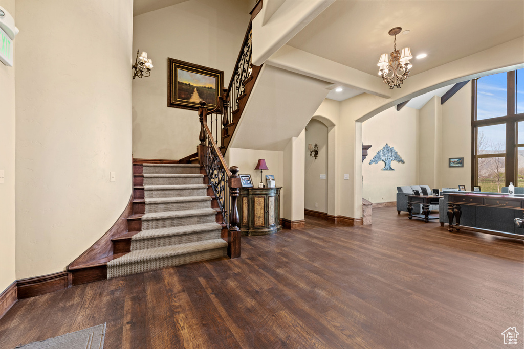 Foyer with arched walkways, wood finished floors, a chandelier, stairway, and recessed lighting