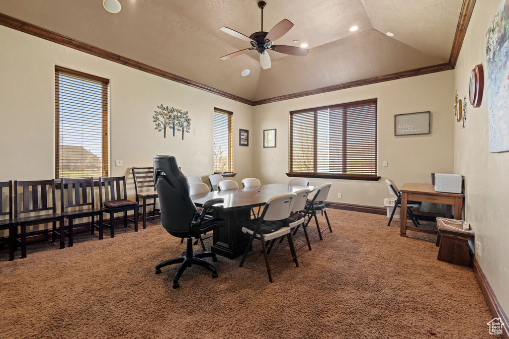 Dining space featuring carpet, vaulted ceiling, ceiling fan, plenty of natural light, and crown molding
