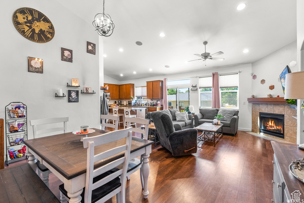 Dining room with recessed lighting, a ceiling fan, a tiled fireplace, dark wood-style floors, and lofted ceiling