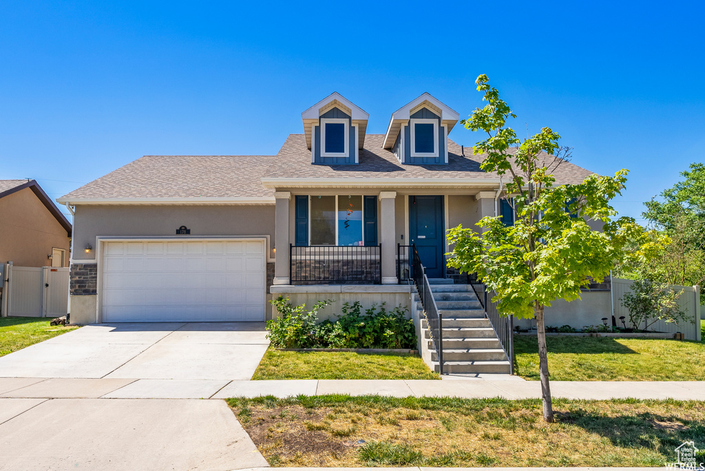 View of front facade featuring stucco siding, a garage, a porch, and driveway