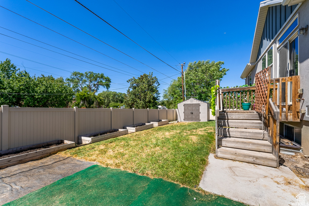 Fenced backyard featuring a storage shed and a wooden deck