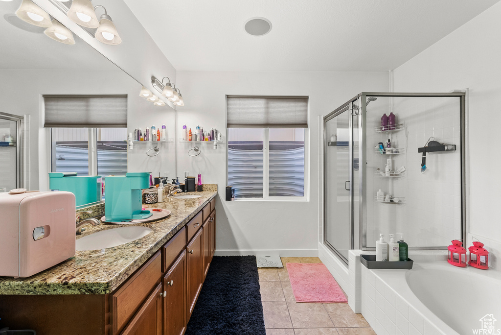 Bathroom featuring double vanity, a shower stall, a garden tub, and tile patterned floors