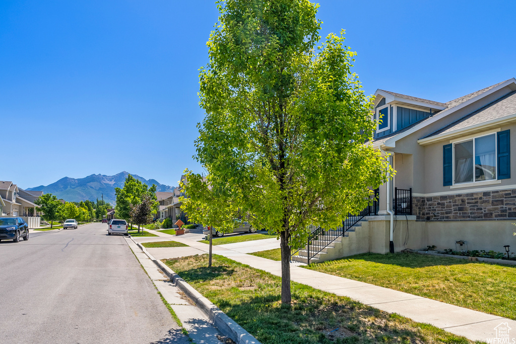 View of asphalt road with sidewalks, curbs, a mountain view, and a residential view