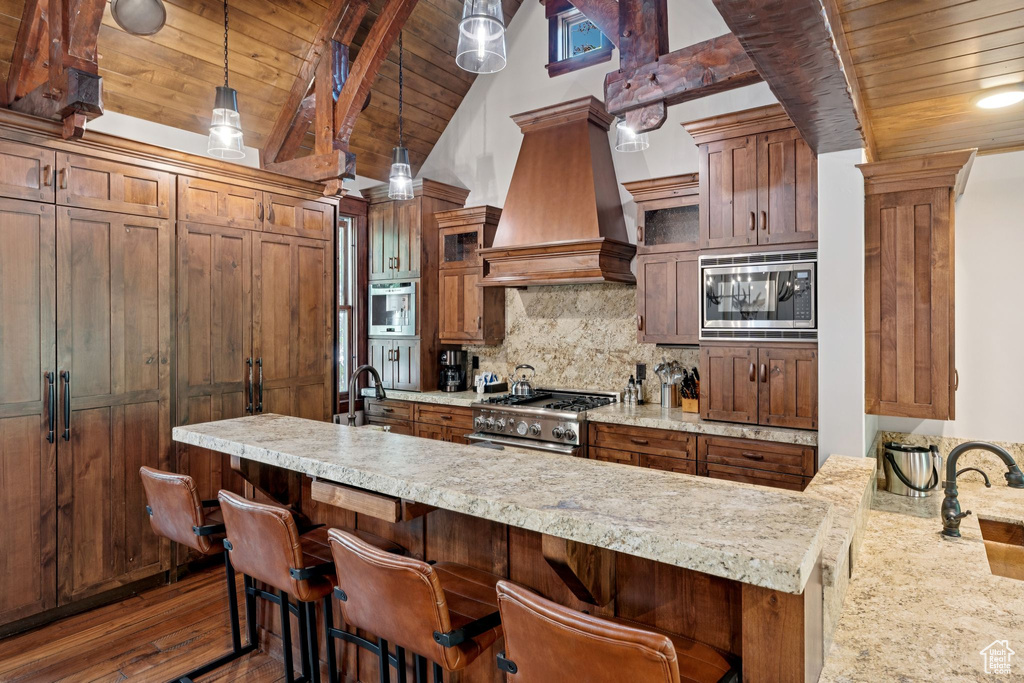 Kitchen featuring stainless steel appliances, custom range hood, wooden ceiling, tasteful backsplash, and glass insert cabinets