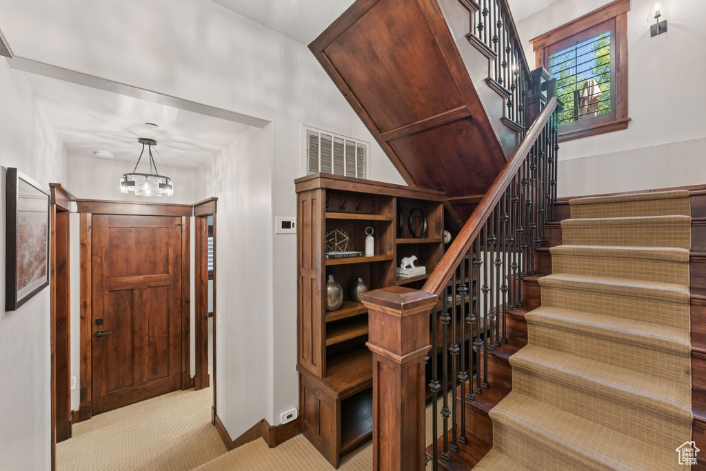 Staircase featuring carpet flooring and a chandelier
