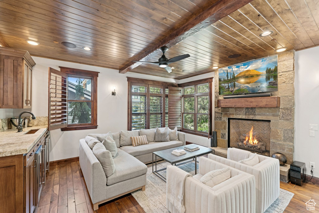 Living area featuring a stone fireplace, wood ceiling, dark wood finished floors, ceiling fan, and wine cooler