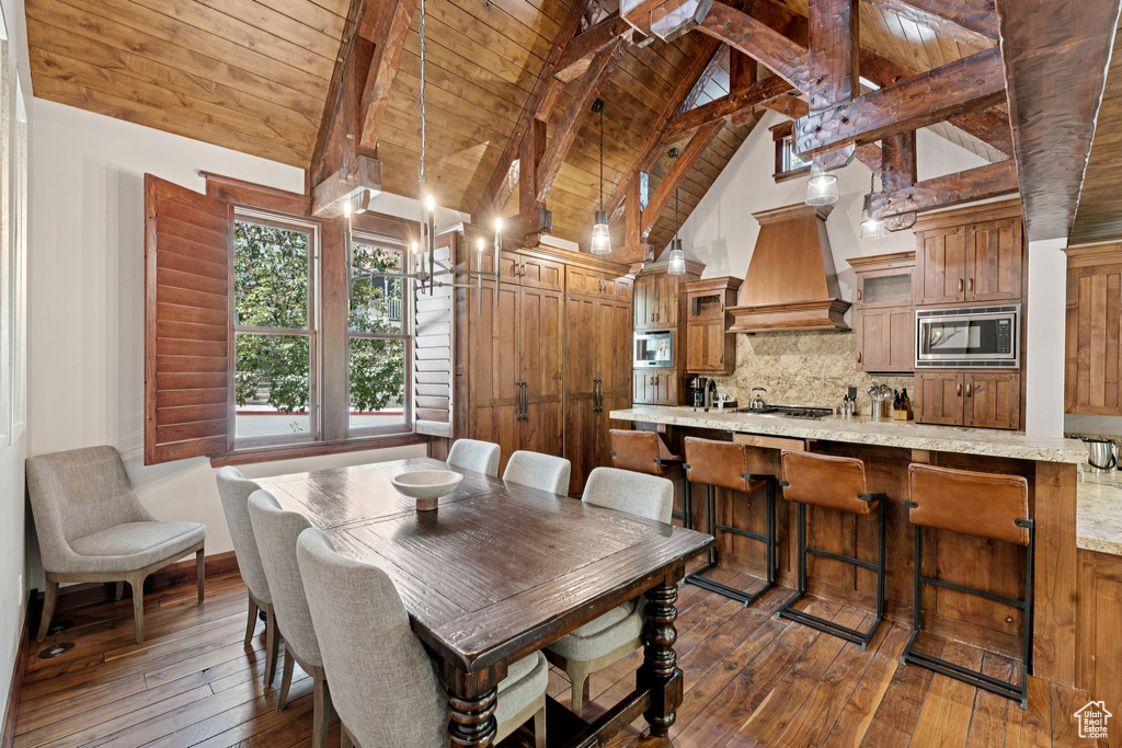 Dining area with a wooden ceiling with exposed beams, dark wood-type flooring, and high vaulted ceiling