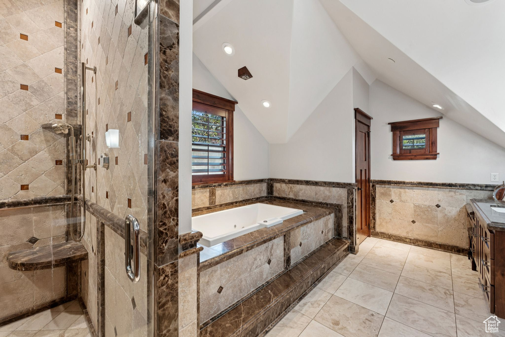 Bathroom featuring tile walls, a tub with jets, a shower stall, lofted ceiling, and vanity