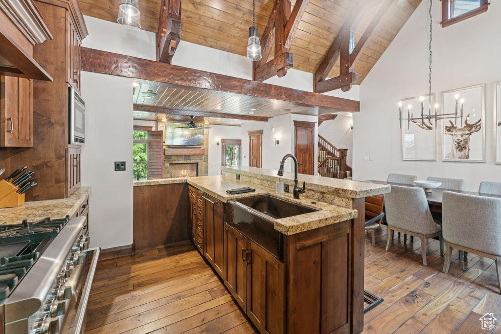 Kitchen featuring stainless steel appliances, wood ceiling, light wood-style flooring, open floor plan, and a warm lit fireplace