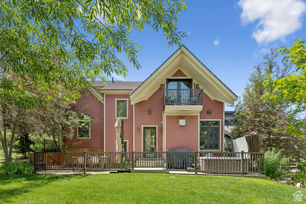Back of house featuring a balcony, a yard, and a wooden deck