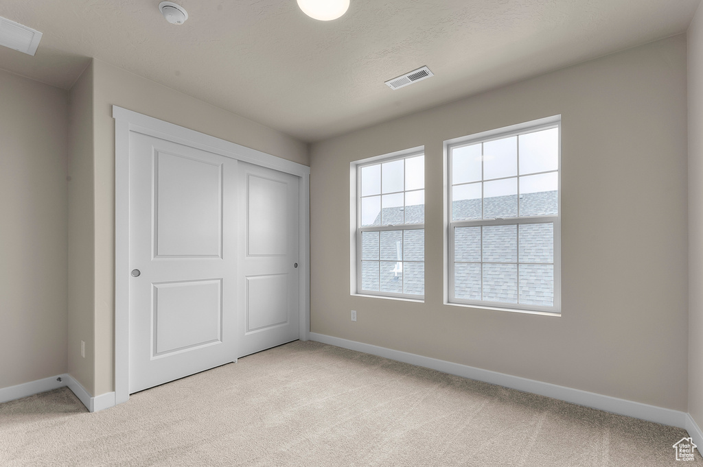 Unfurnished bedroom with light carpet and a closet