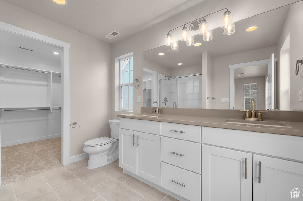 Bathroom featuring double vanity, a shower stall, a walk in closet, recessed lighting, and tile patterned floors