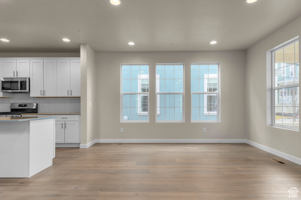Kitchen with appliances with stainless steel finishes, light wood-style flooring, recessed lighting, and backsplash