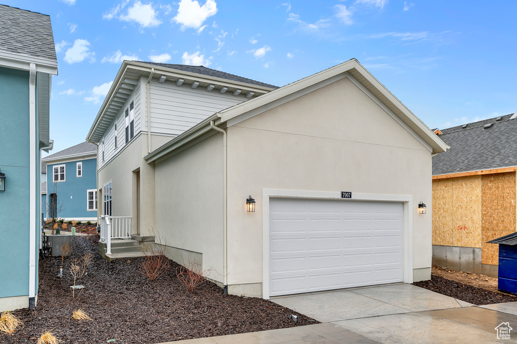 View of side of home featuring concrete driveway, a garage, and stucco siding