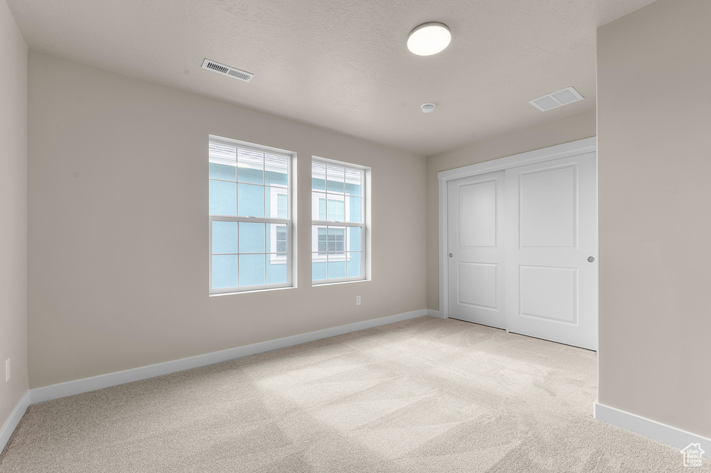 Unfurnished bedroom featuring light carpet and a closet