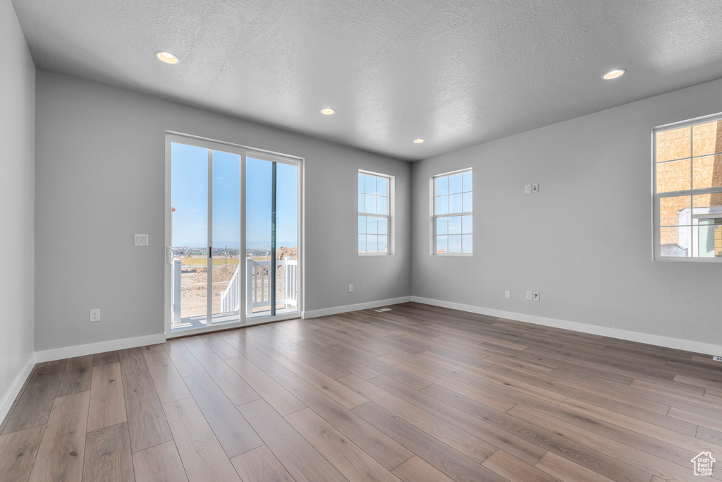 Unfurnished room with wood finished floors, a textured ceiling, and recessed lighting