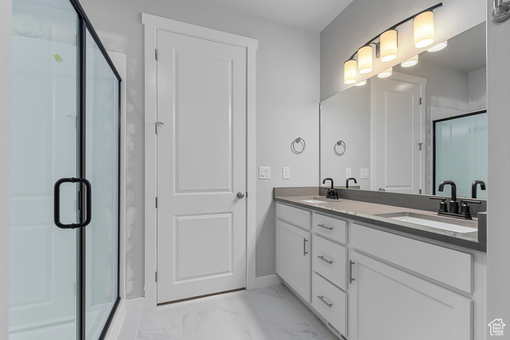 Full bathroom featuring double vanity, a stall shower, and marble look tile flooring