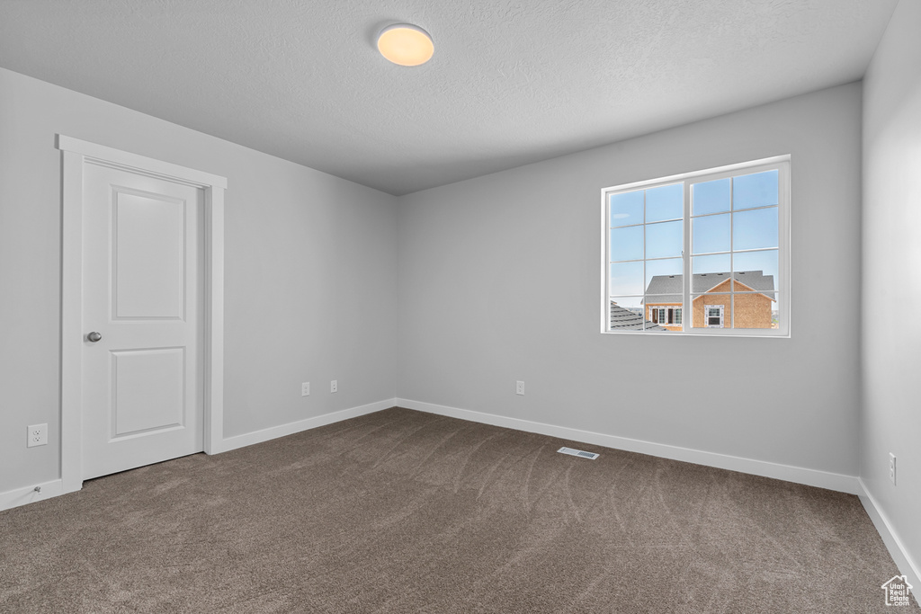 Unfurnished room with dark colored carpet and a textured ceiling