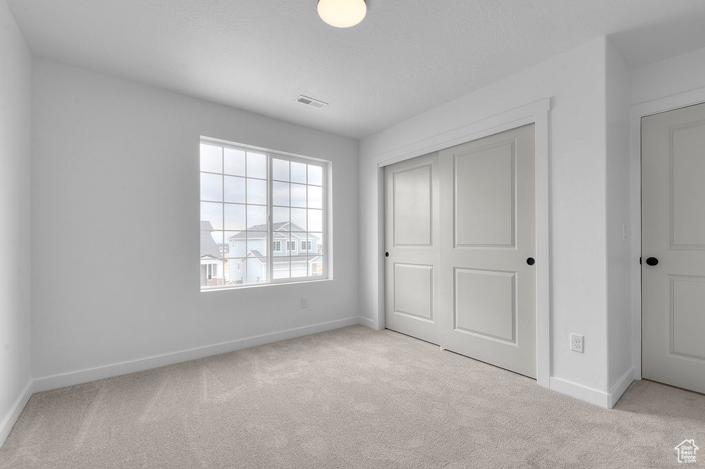 Unfurnished bedroom featuring carpet flooring and a closet