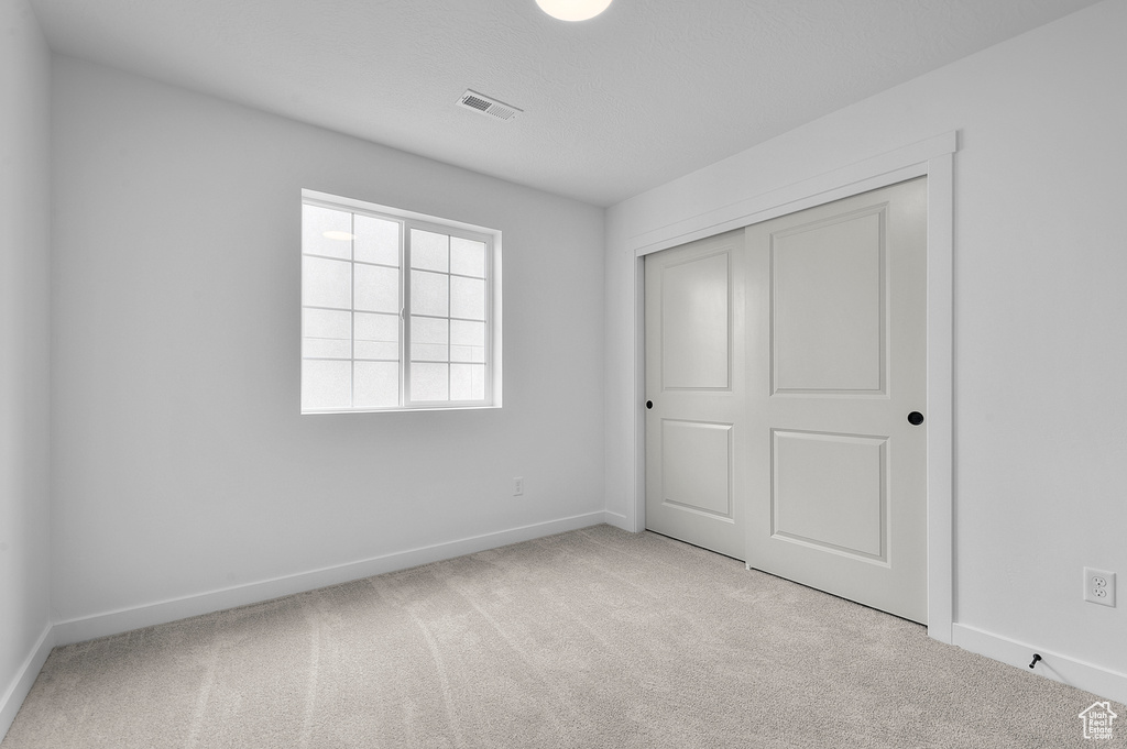 Unfurnished bedroom featuring carpet and a closet