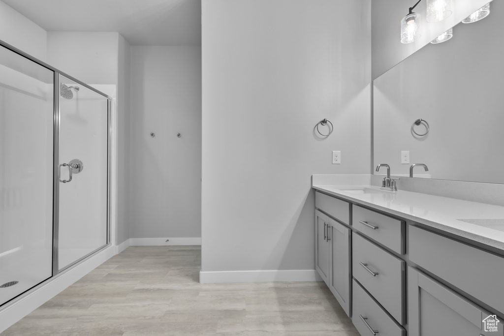 Full bathroom with double vanity, wood finished floors, and a stall shower