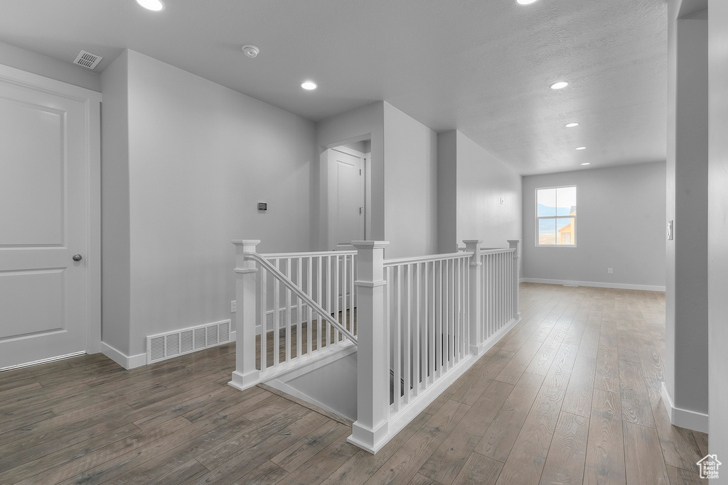 Corridor featuring an upstairs landing, hardwood / wood-style floors, and recessed lighting