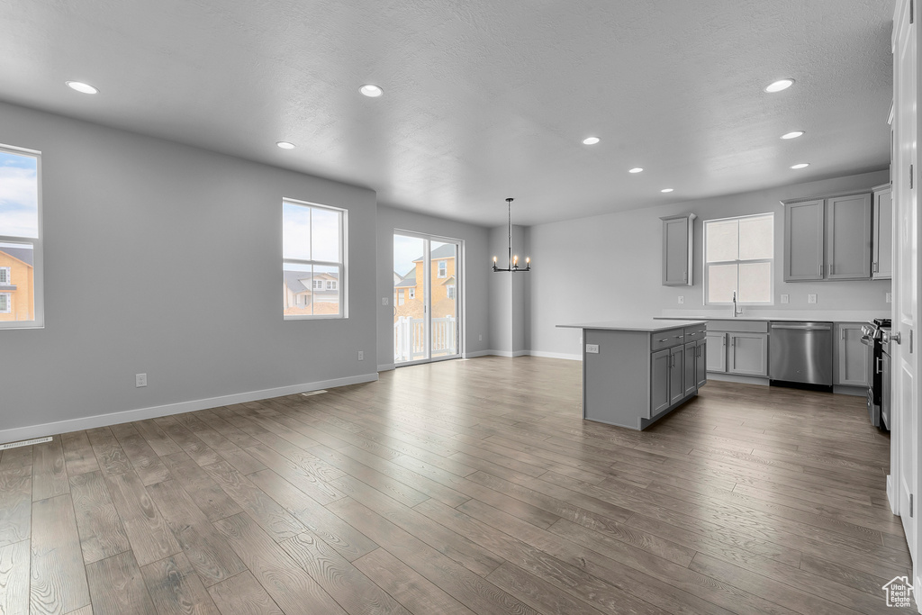 Kitchen with gray cabinets, stainless steel dishwasher, a chandelier, a kitchen island, and recessed lighting