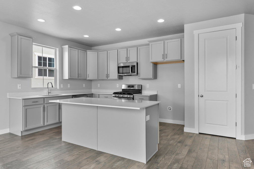 Kitchen with stainless steel appliances, gray cabinetry, a kitchen island, light countertops, and recessed lighting
