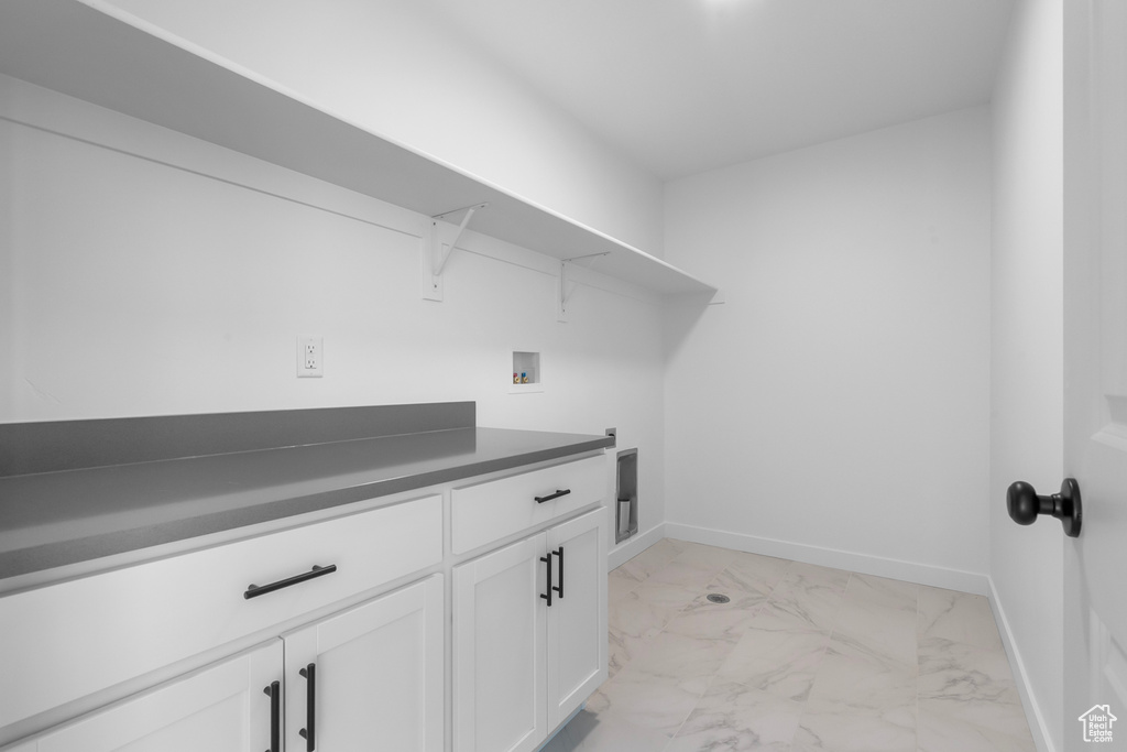 Laundry area featuring light marble finish floors, washer hookup, and cabinet space