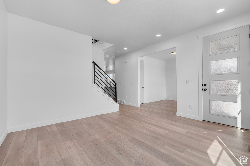 Unfurnished living room with stairway, light wood-style floors, and recessed lighting