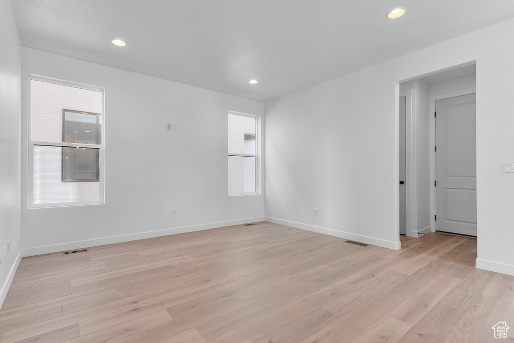 Empty room with light wood-style floors and recessed lighting