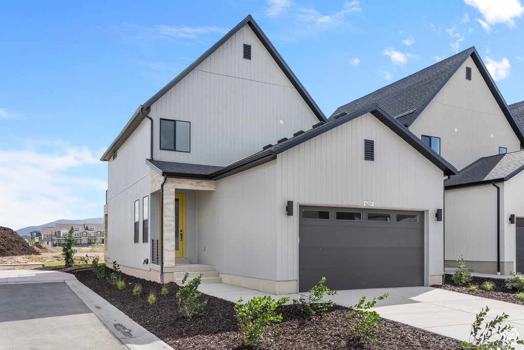 Modern farmhouse style home featuring driveway, a garage, and a shingled roof