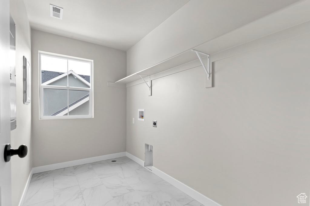 Laundry room with electric dryer hookup, hookup for a washing machine, and light marble finish flooring