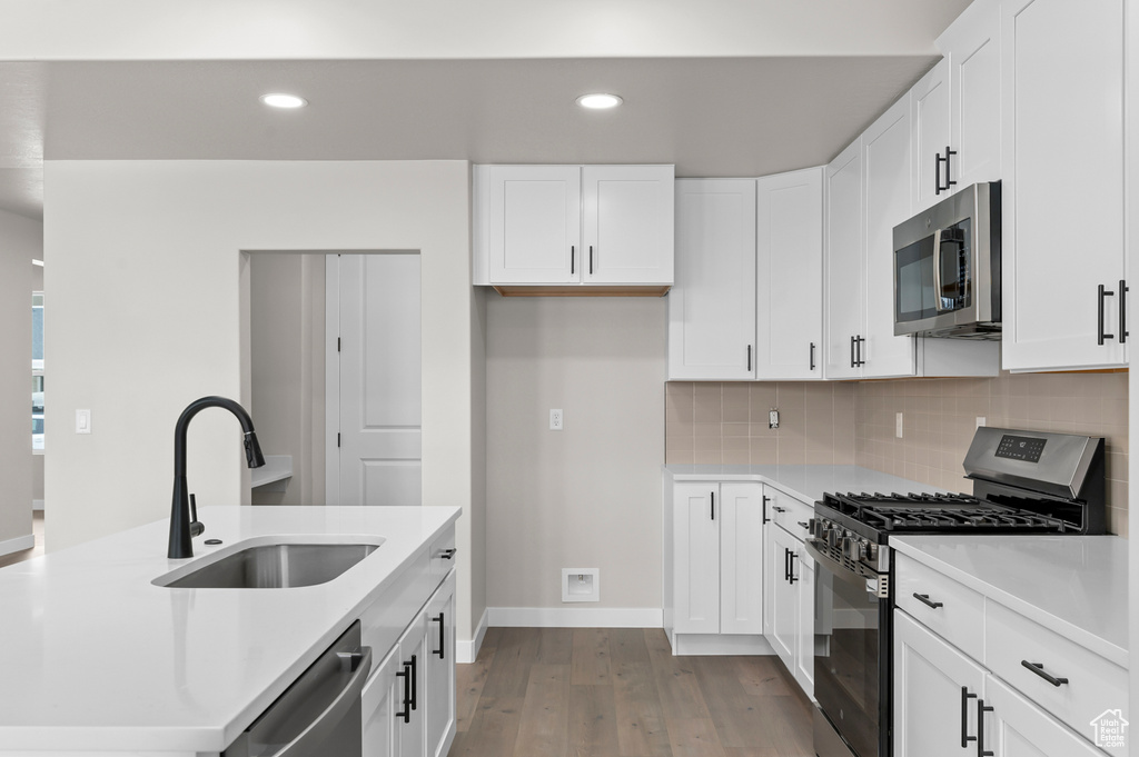 Kitchen featuring appliances with stainless steel finishes, wood finished floors, tasteful backsplash, light countertops, and recessed lighting