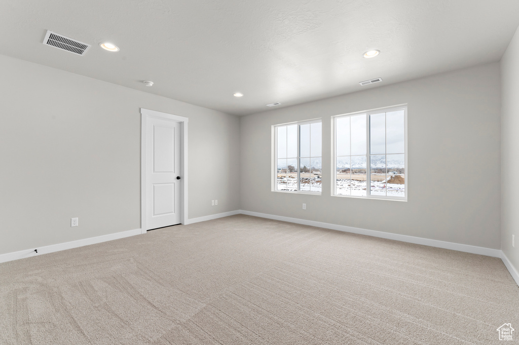 Empty room with light carpet and recessed lighting