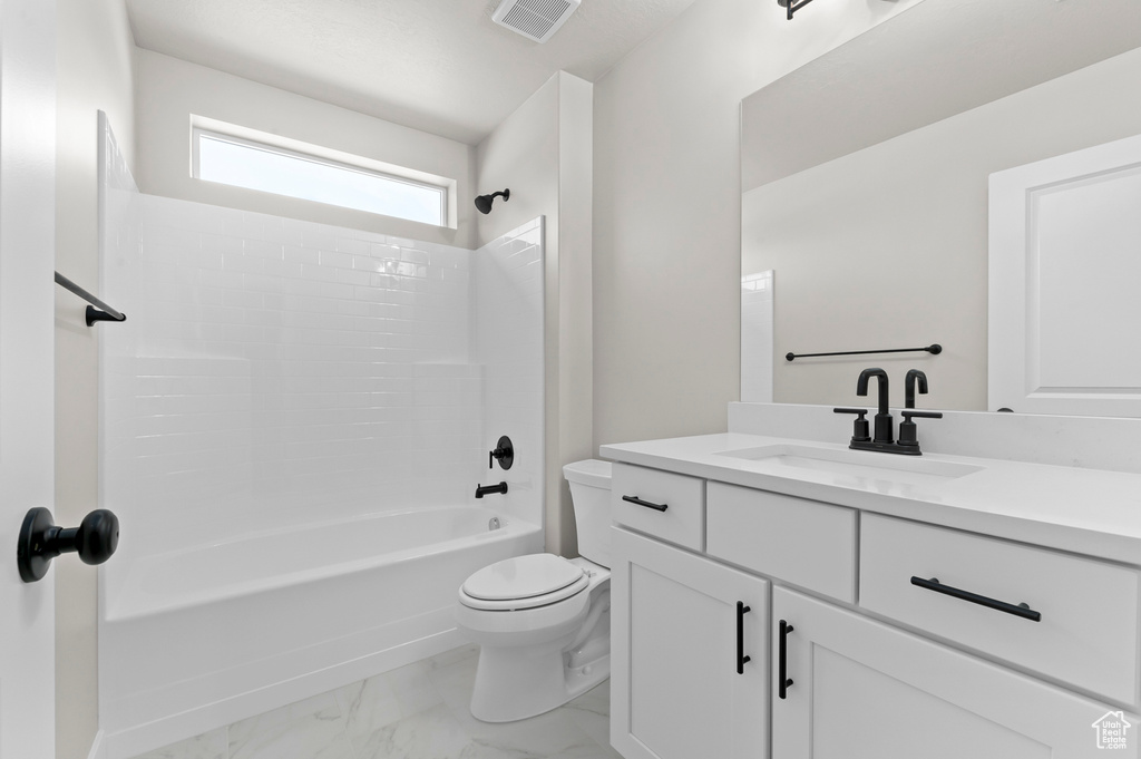 Full bath with vanity, marble look tiles, and  shower combination