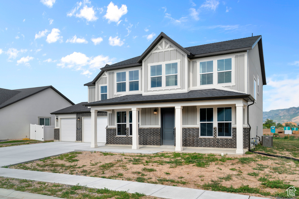 View of front of house with board and batten siding, covered porch, driveway, an attached garage, and a mountain view