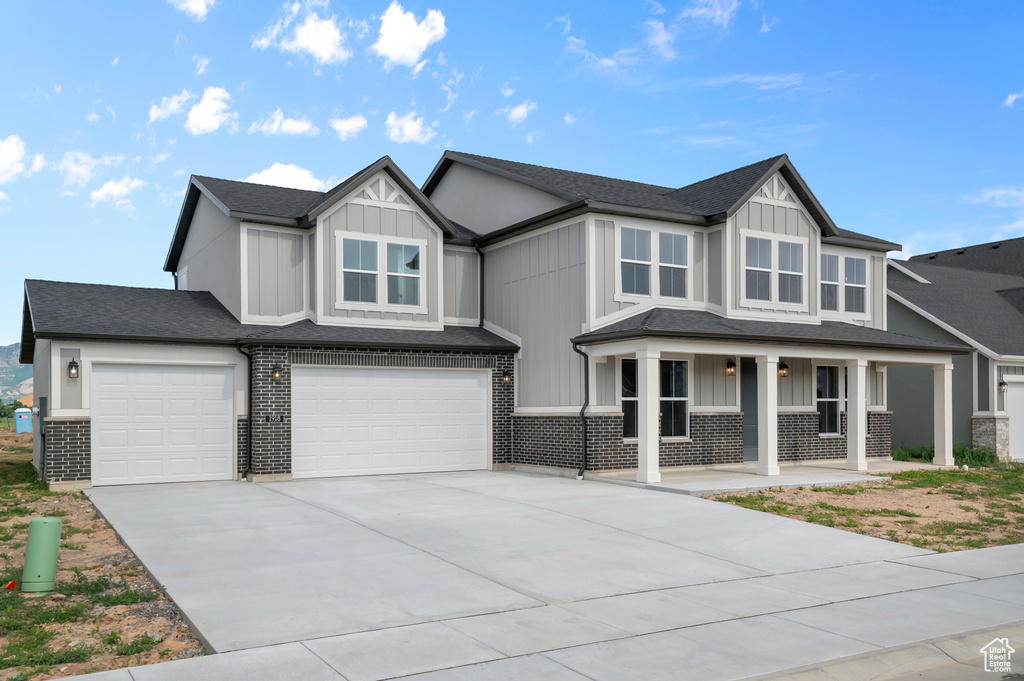 View of front of home featuring covered porch, board and batten siding, an attached garage, driveway, and a shingled roof