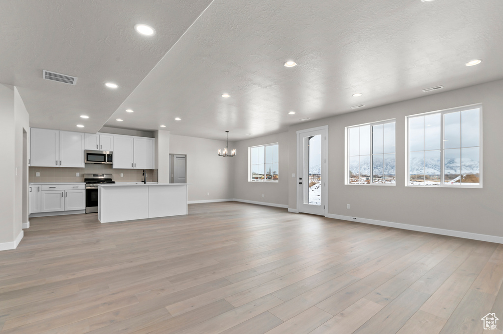Unfurnished living room featuring a chandelier, recessed lighting, and light wood-type flooring