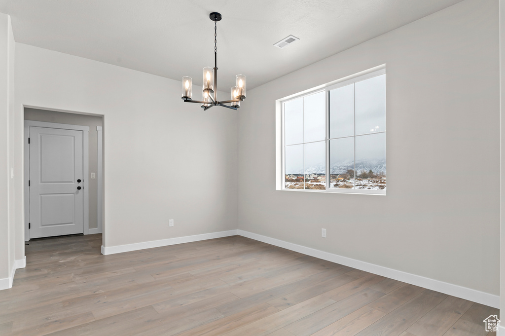 Empty room with a chandelier and light wood finished floors