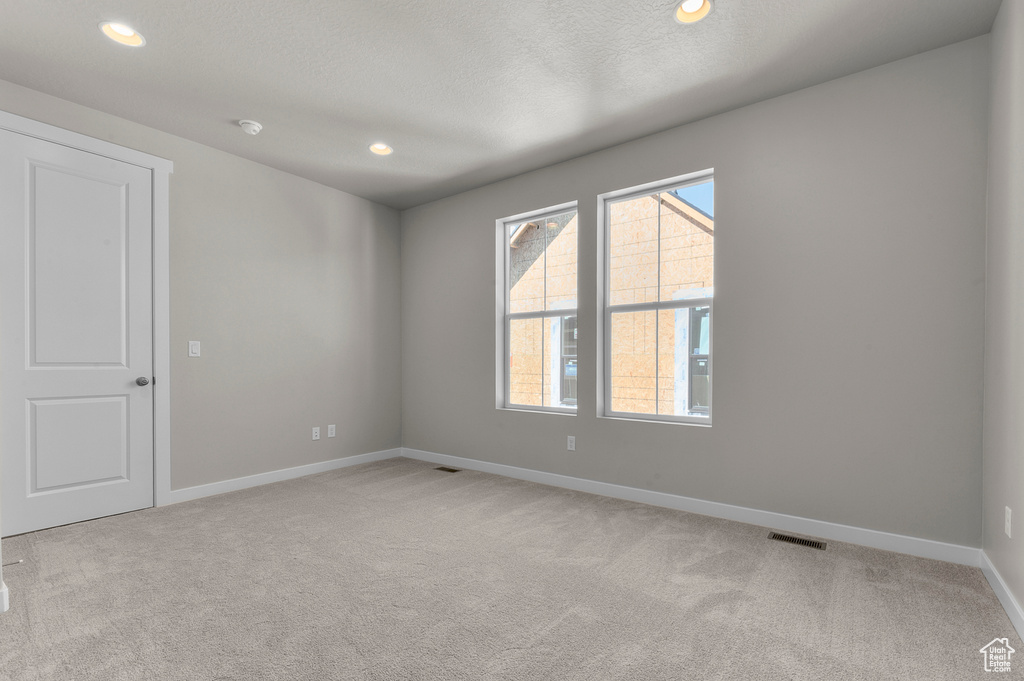 Empty room featuring light colored carpet, recessed lighting, and a textured ceiling