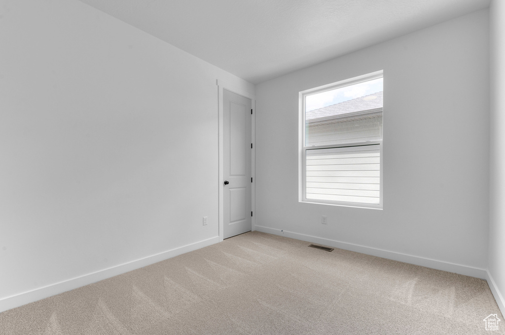 Spare room featuring light colored carpet and baseboards
