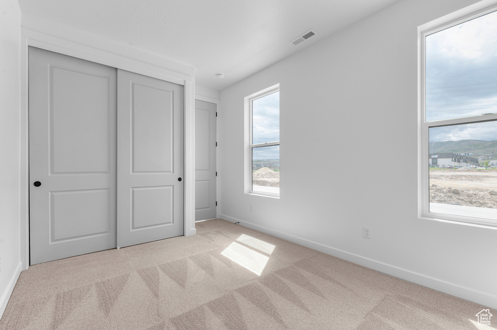 Unfurnished bedroom with light carpet and a closet