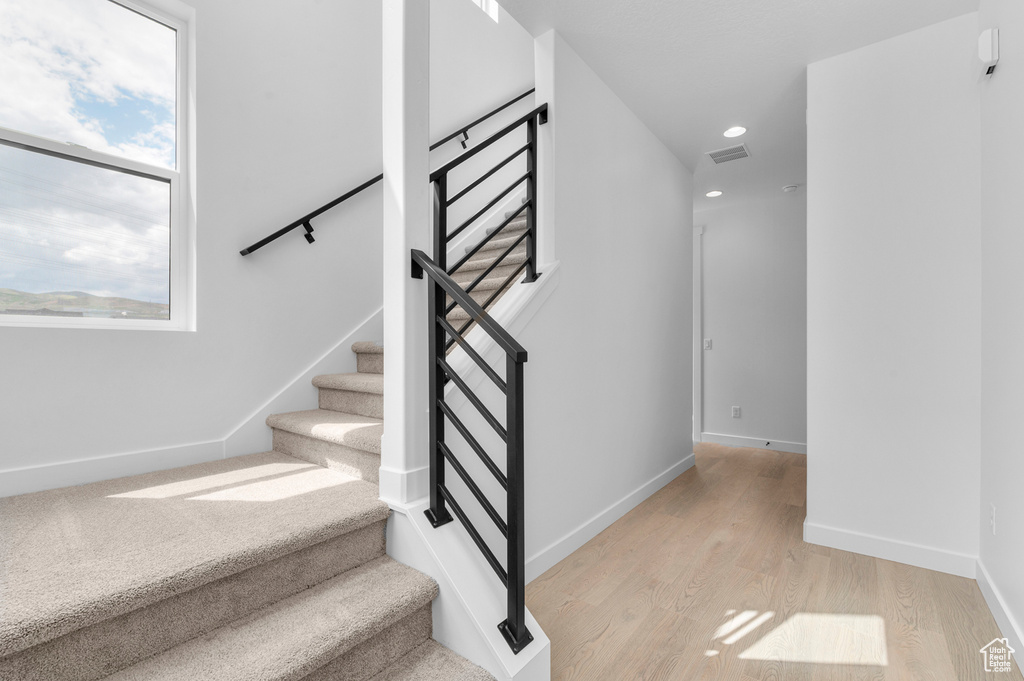 Stairs with wood finished floors, plenty of natural light, and recessed lighting