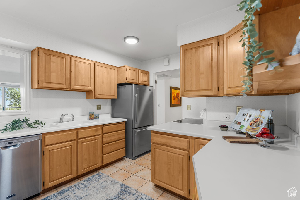 Kitchen with stainless steel appliances, light countertops, and light tile patterned flooring