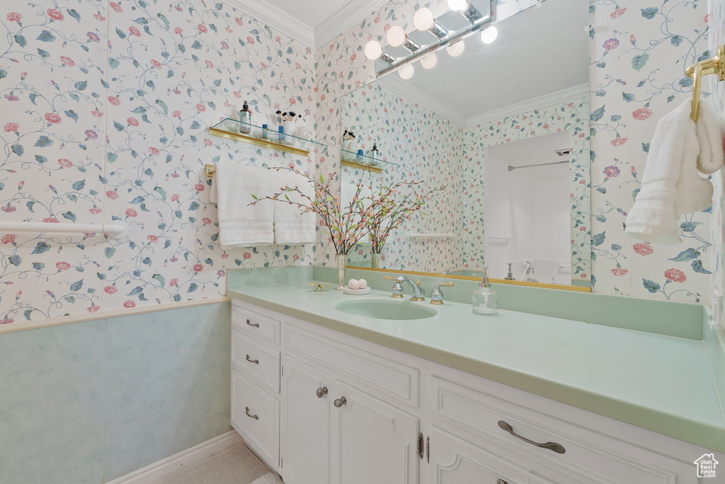 Bathroom featuring wallpapered walls, ornamental molding, and vanity