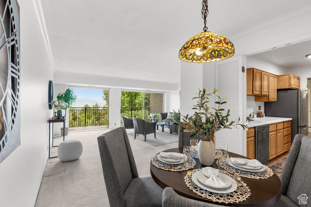 Dining area featuring carpet floors, ornamental molding, and a textured ceiling