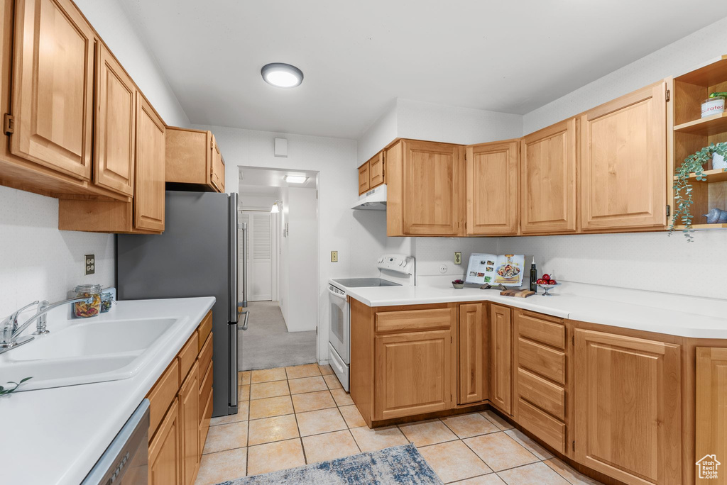 Kitchen with stainless steel appliances, under cabinet range hood, light countertops, and open shelves