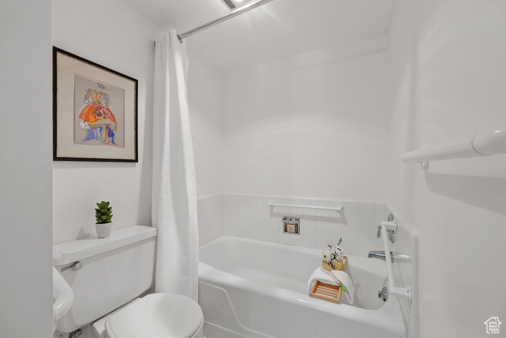 Bathroom featuring toilet and shower / bath combo with shower curtain