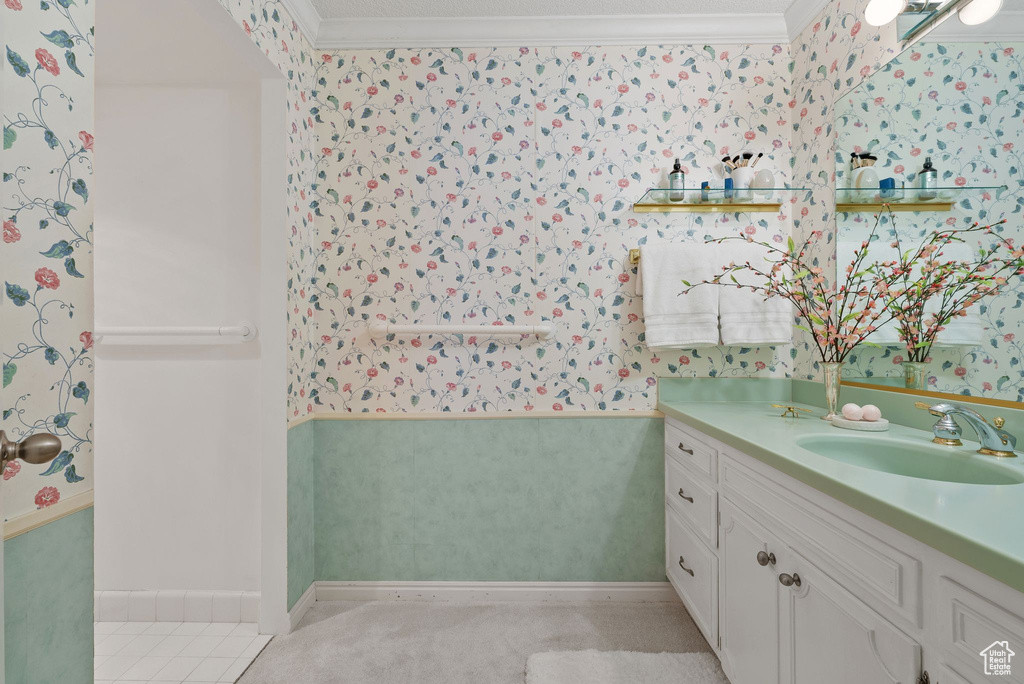 Bathroom featuring wallpapered walls, vanity, and ornamental molding